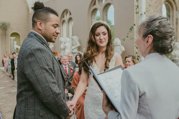 Bride and groom at alter with officiant holding hands