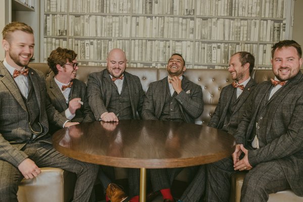 Groom and groomsmen in brown suits sitting beside table