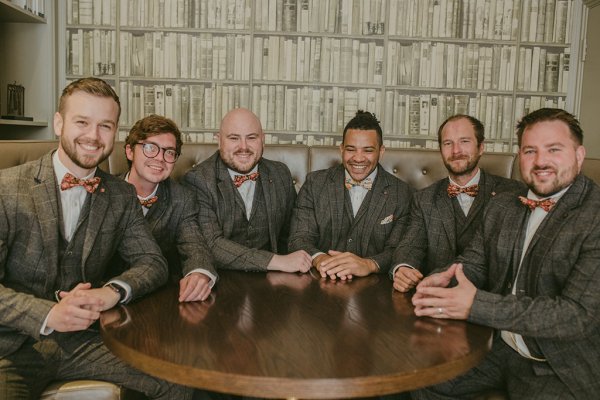 Groom and groomsmen in brown suits sitting beside table