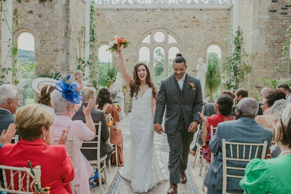 Bride hand in the air holding flowers just wed guests seated clapping