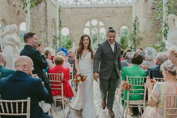 Bride hand in the air holding flowers just wed guests seated clapping