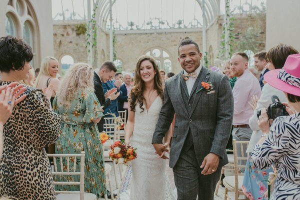 Bride hand in the air holding flowers just wed guests seated clapping