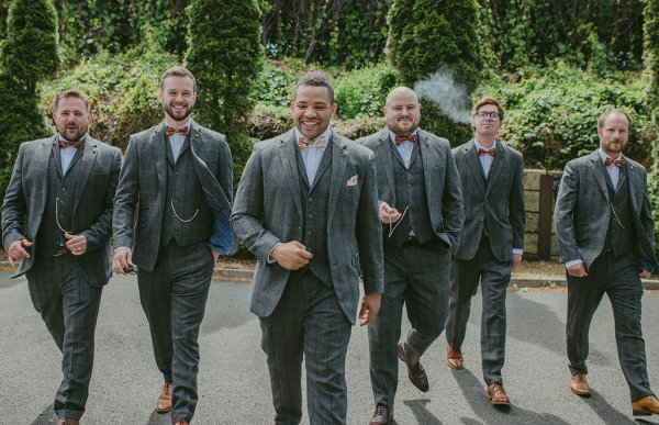 Groom and groomsmen walking exterior garden setting