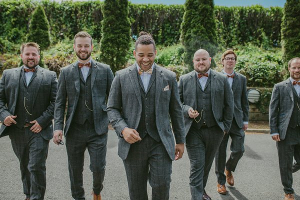 Groom and groomsmen walking exterior garden setting