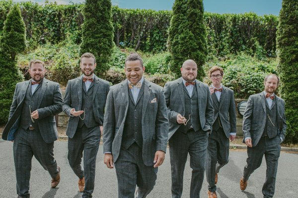 Groom and groomsmen walking exterior garden setting