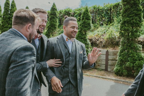 Groom and groomsmen walking exterior garden setting