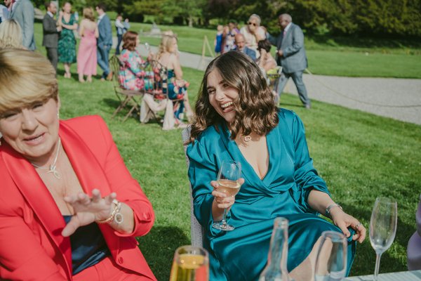 Woman wavy hair blue dress laughing laughs on grass