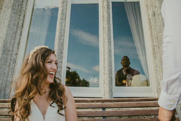 Groom reflection bride smiles on bench