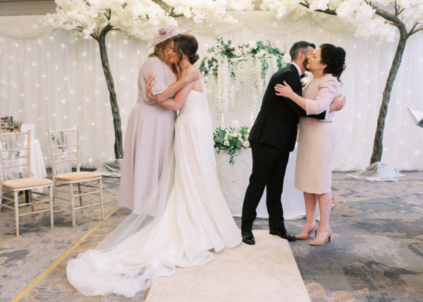 Bride hugs mother and groom hugs mother at alter