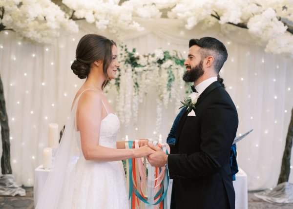 Bride and groom at the alter holding hands reading vows lights in background