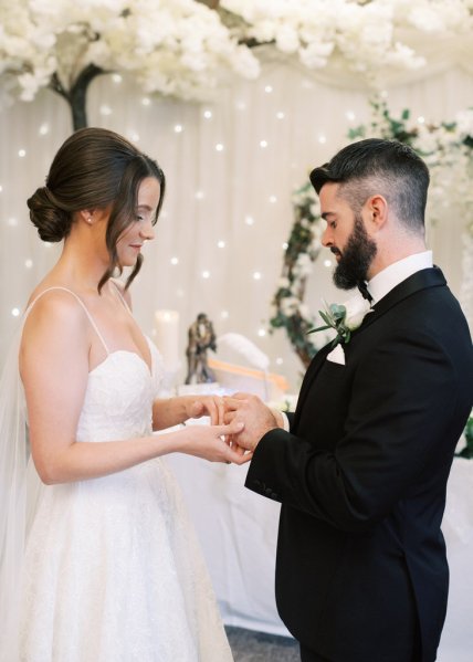 Bride and groom at the alter holding hands reading vows