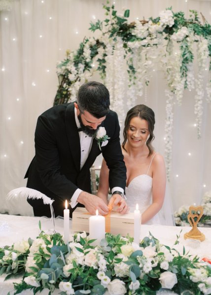 Bride and groom signing documents at table marriage certificates and candles