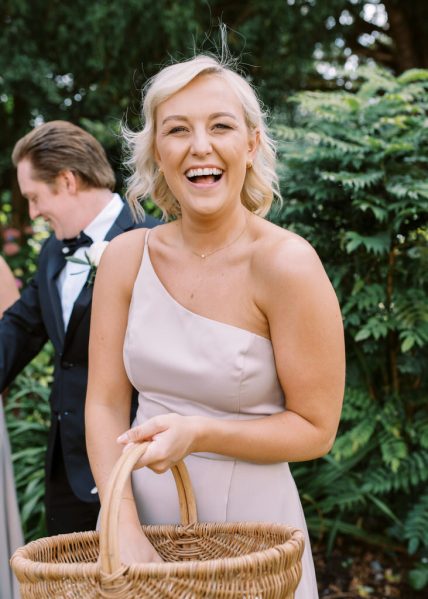 Bridesmaid holding basket laughs