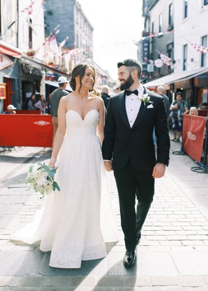 Bride and groom walk through town hand in hand down the road