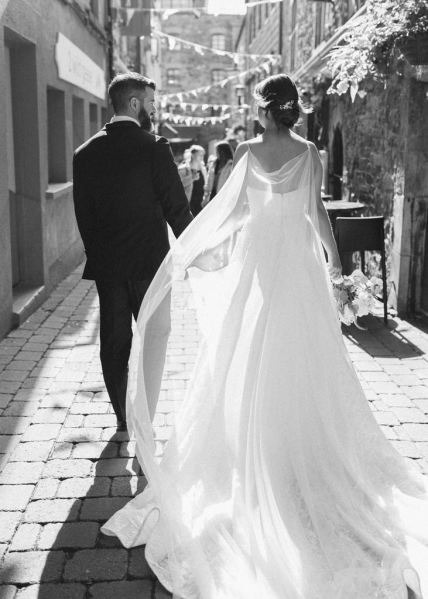 Bride and groom walk hand in hand black and white image