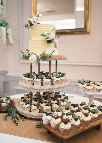 Up close detail of creamy cupcakes with fruit on top and wedding cake