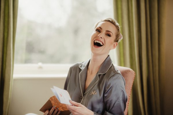 Bride laughs beside window getting ready