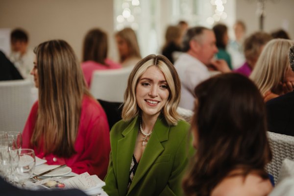 Woman in green suit jacket smiling/talking