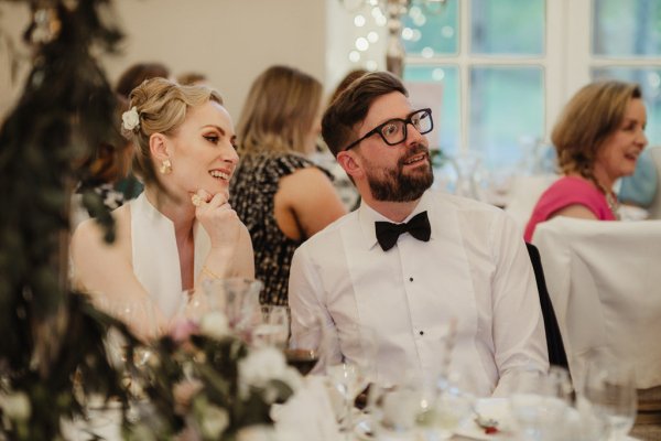 Bride and groom smile during speeches