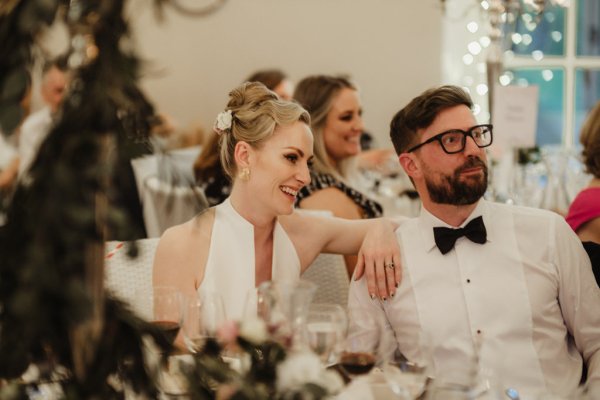 Bride and groom looking at guest give speech