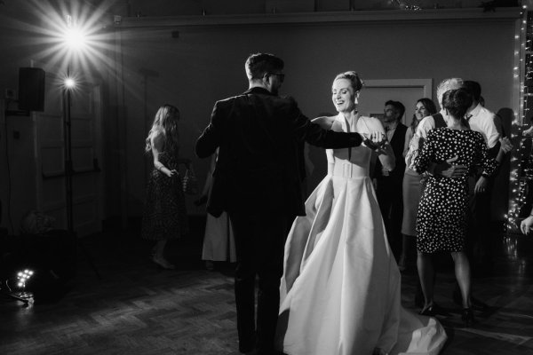 Black and white image of bride and groom on the dancefloor lights