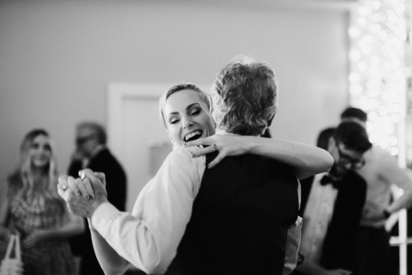 Black and white image of father and bride dancing on the dancefloor smiling laughing