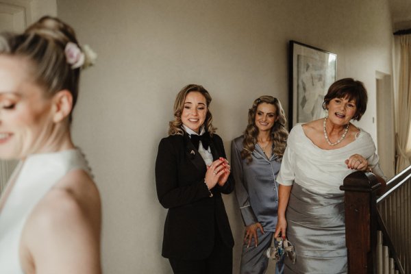 Bride and sister guest in suit laughing