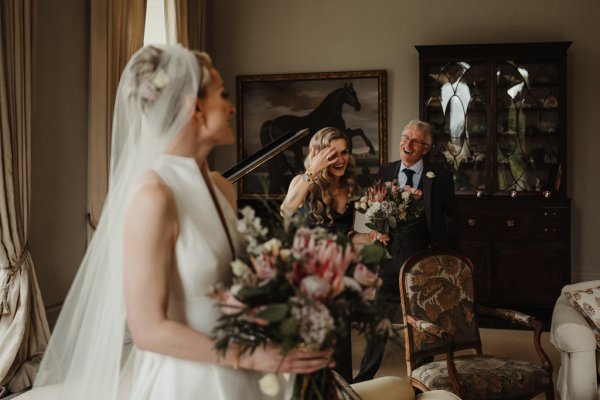 Bride holding bouquet father in background