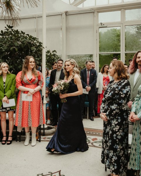 Bridesmaids in suede blue dress walks down the aisle