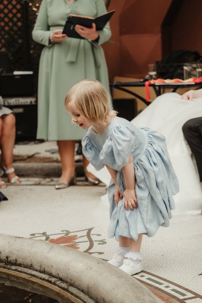 Little girl in blue looking at fountain