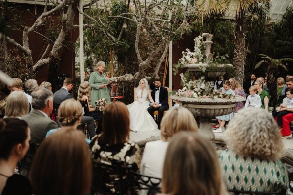 Officiant bride and groom guest and fountain shot