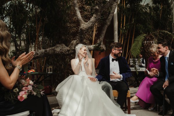 Bride clapping sitting beside groom