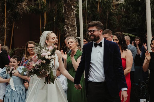 Bride holding bouquet hand in hand with groom