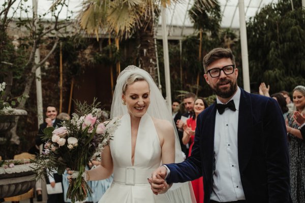 Bride holding bouquet hand in hand with groom