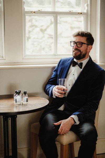 Groom sitting at window drinking whiskey