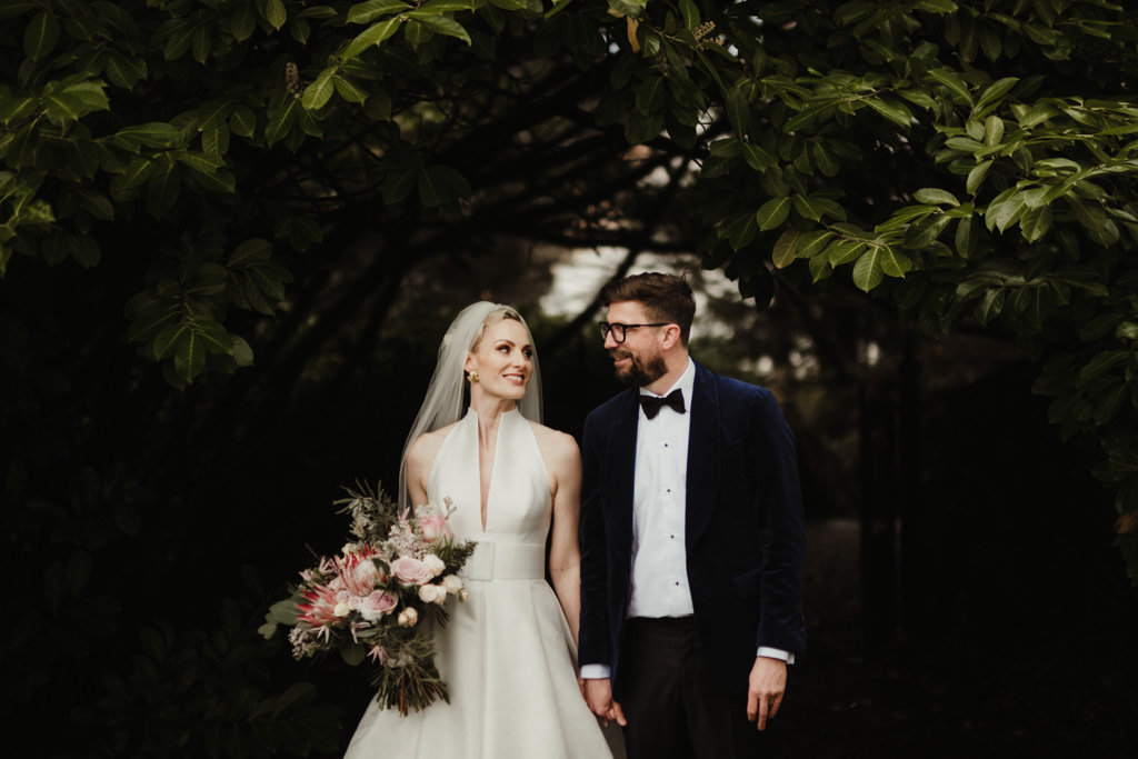 Bride and groom in park bouquet in hand