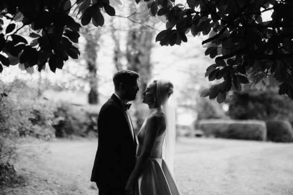 Black and white image of bride and groom holding hands in park