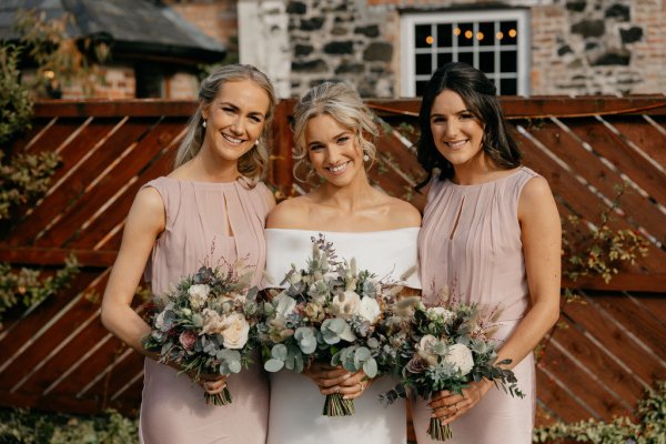 Bride and bridesmaids holding bouquets exterior setting