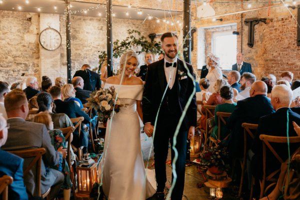 Bride and groom just wed confetti guests exiting