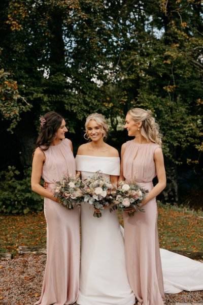 Bride and bridesmaids holding flowers exterior setting