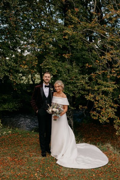 Bride and groom couple surrounded by trees in park smiling