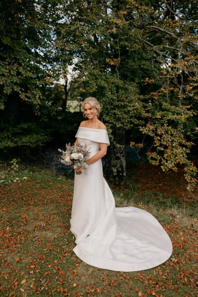 Bride surrounded by trees in park smiling