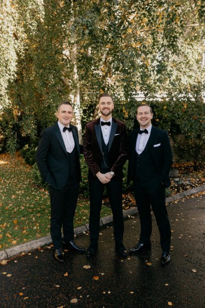 Groom and groomsmen standing in forest