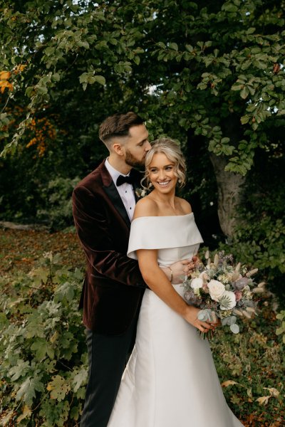 Bride and groom couple surrounded by trees in park smiling