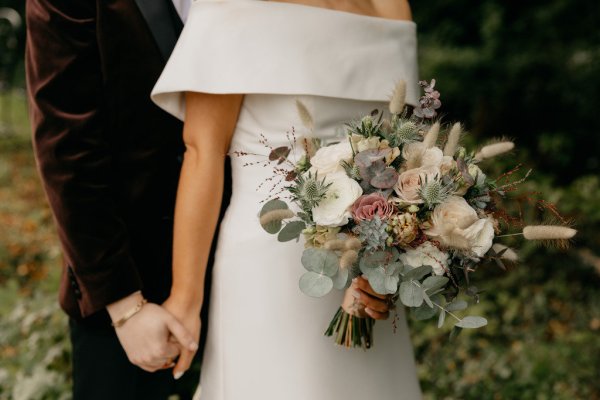 Close up detail of couples hands bride and groom holding hands bouquet/flowers