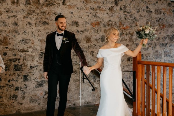 Bride and groom holding hands bouquet in the air