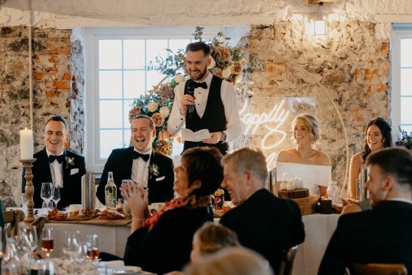 Groom reading speech bride laughing dining room interior