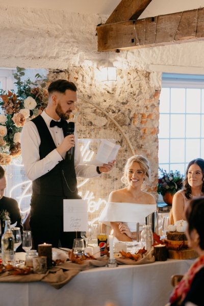 Groom reading speech bride laughing dining room interior