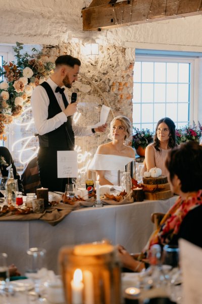 Bride looking at groom giving speech guests