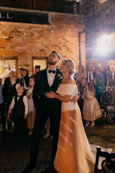 Couple bride groom and guests watch and look at firework display